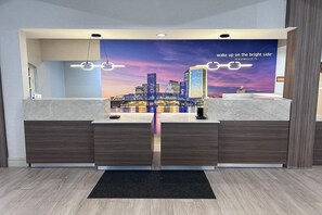 A hotel reception desk with a cityscape mural, a modern design, and a black doormat.