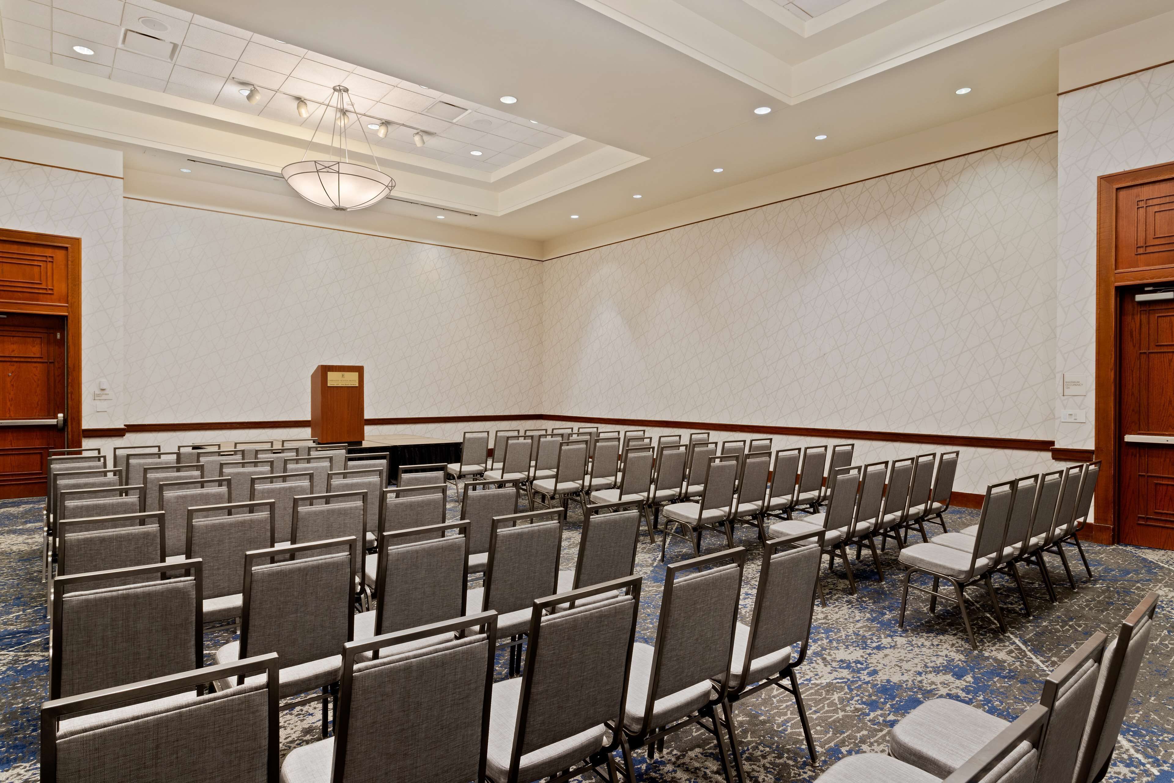 A conference room with rows of chairs, a podium, and a patterned carpet.