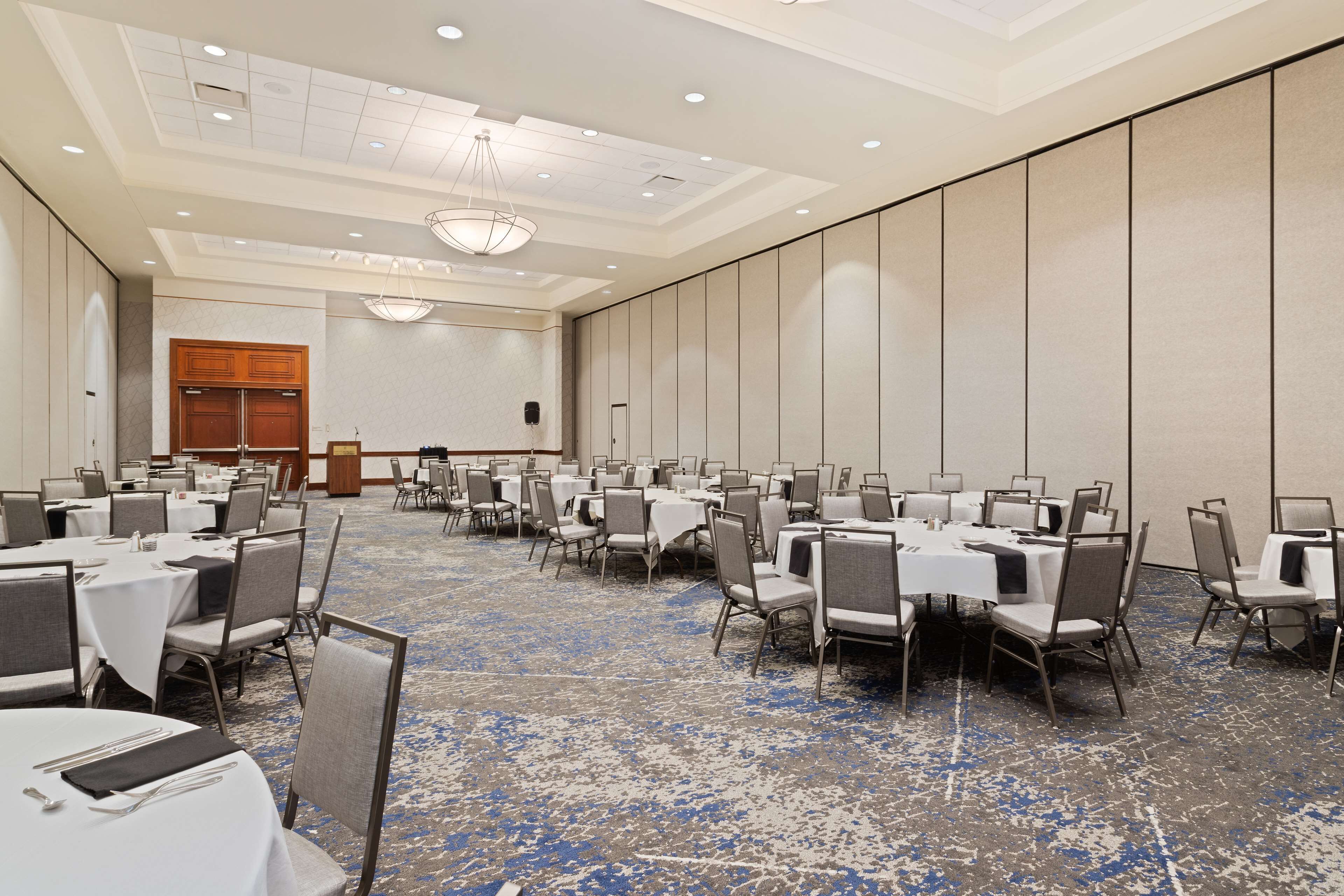 A conference room with round tables, chairs, and a stage.