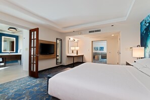 Una habitación de hotel con una cama grande, una televisión, un baño con espejo y un cuadro en la pared.