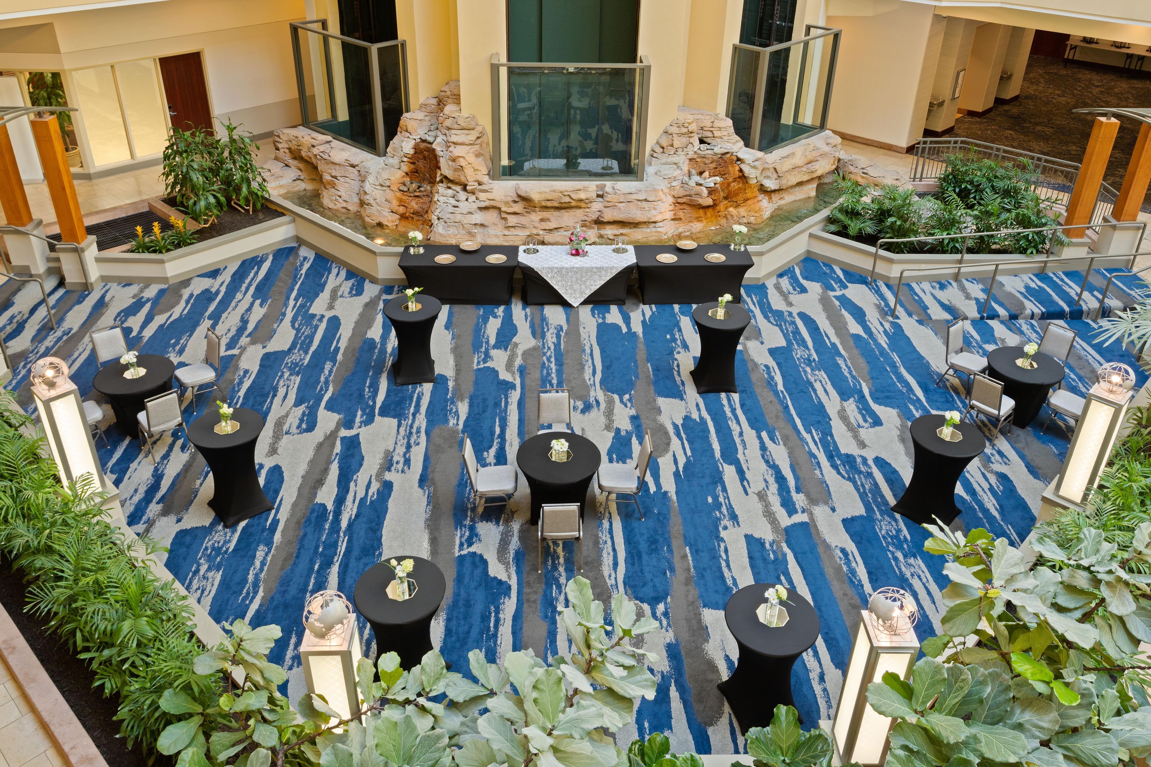A spacious outdoor area with a blue patterned carpet, multiple tables with chairs, and a central seating area with a table and chairs.