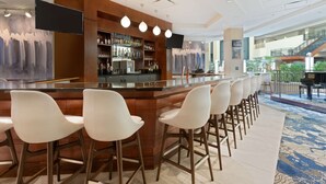 Zona de bar con una barra larga, varios taburetes y una buena selección de bebidas.