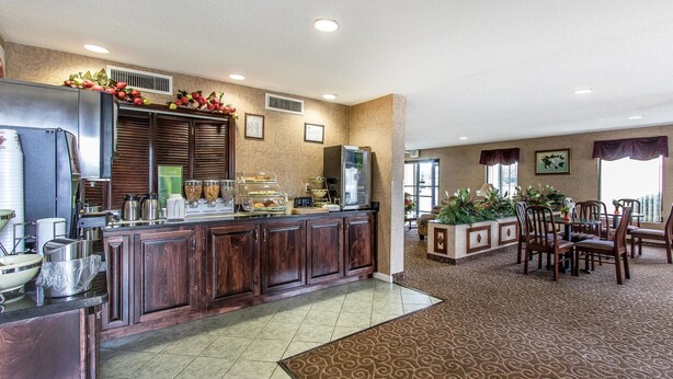 A hotel lobby with a reception desk, a buffet area, and a dining area with chairs and tables. - Quality Inn Andalusia (Andalusia)