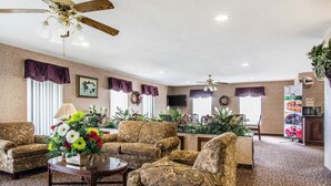 A spacious living room with patterned sofas, a coffee table, and a ceiling fan. - Quality Inn Andalusia (Andalusia)