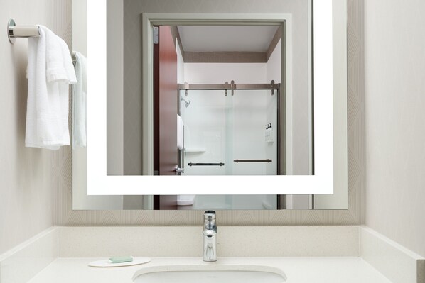 A bathroom with a large mirror, a white sink, and a towel rack.