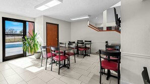 A dining area with a view of a swimming pool, a staircase, and a potted plant.