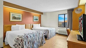 A hotel room with two beds, a desk with a TV, and a window with a view.