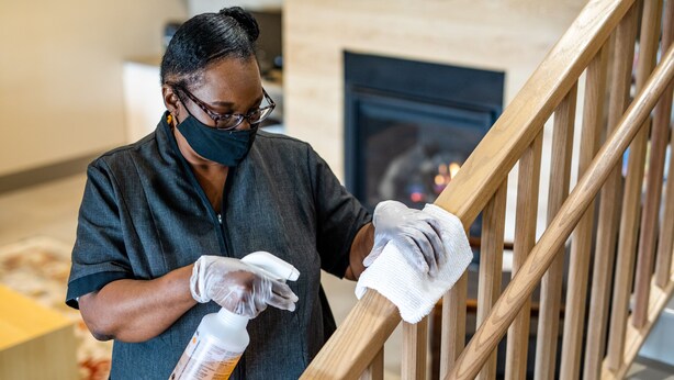 A person cleaning a wooden staircase with a spray bottle and cloth. - Country Inn & Suites by Radisson, Nashville, TN (Nashville)