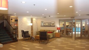 A spacious living area with a staircase, a sofa, a chair, and a coffee table. - Country Inn & Suites by Radisson, Nashville, TN (Nashville)