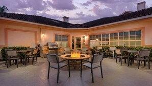 An outdoor patio with a fire pit, seating, and a grill area. - Residence Inn by Marriott West Palm Beach (West Palm Beach)