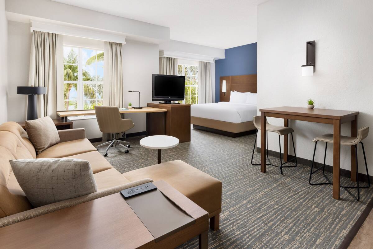 Habitación de hotel con cama, escritorio, sofá y televisor.