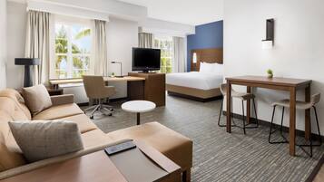 A hotel room with a bed, a desk, a sofa, and a TV.