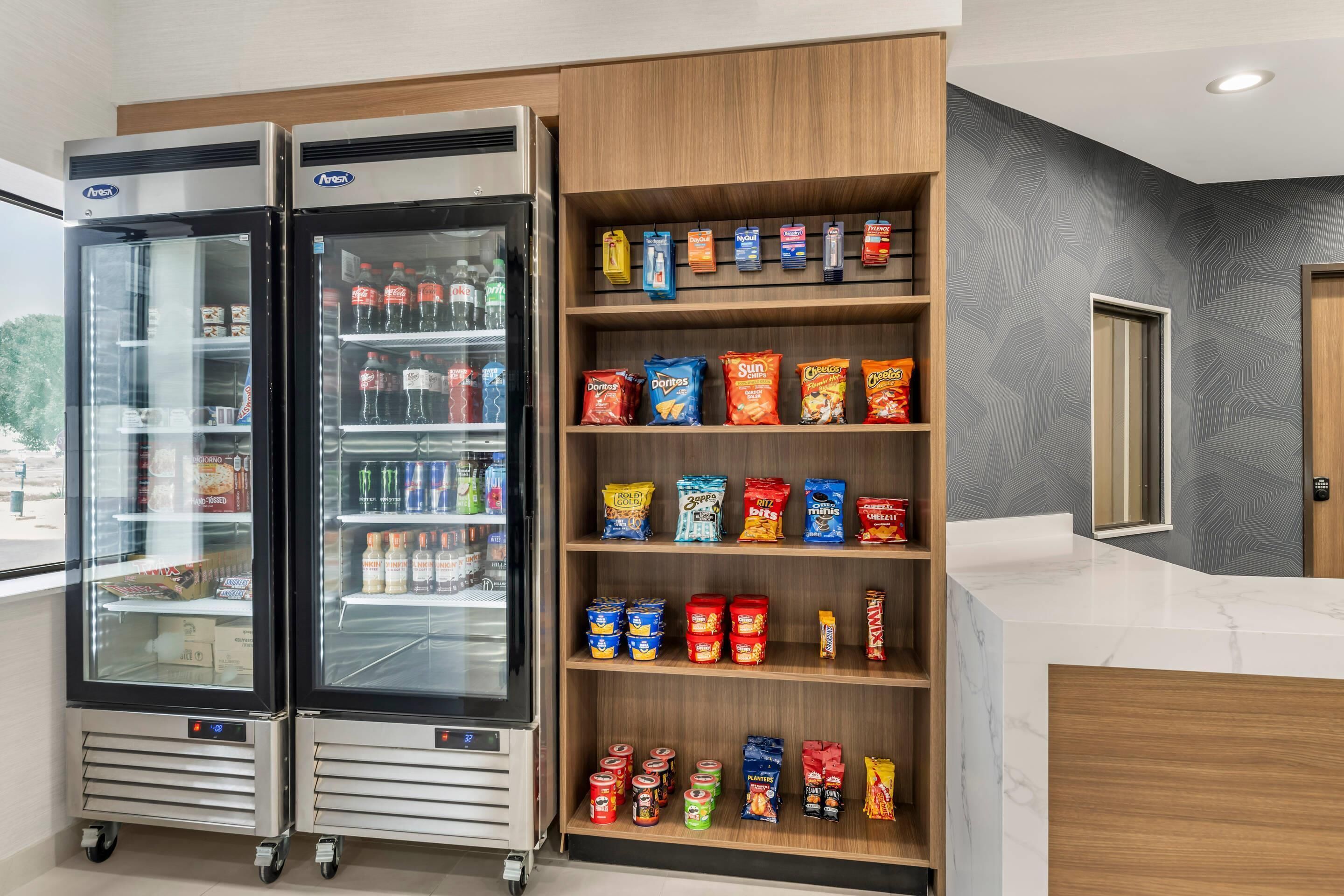 Een gekoelde vitrine met verschillende drankjes en snacks, waaronder frisdranken, water in flessen en chips.