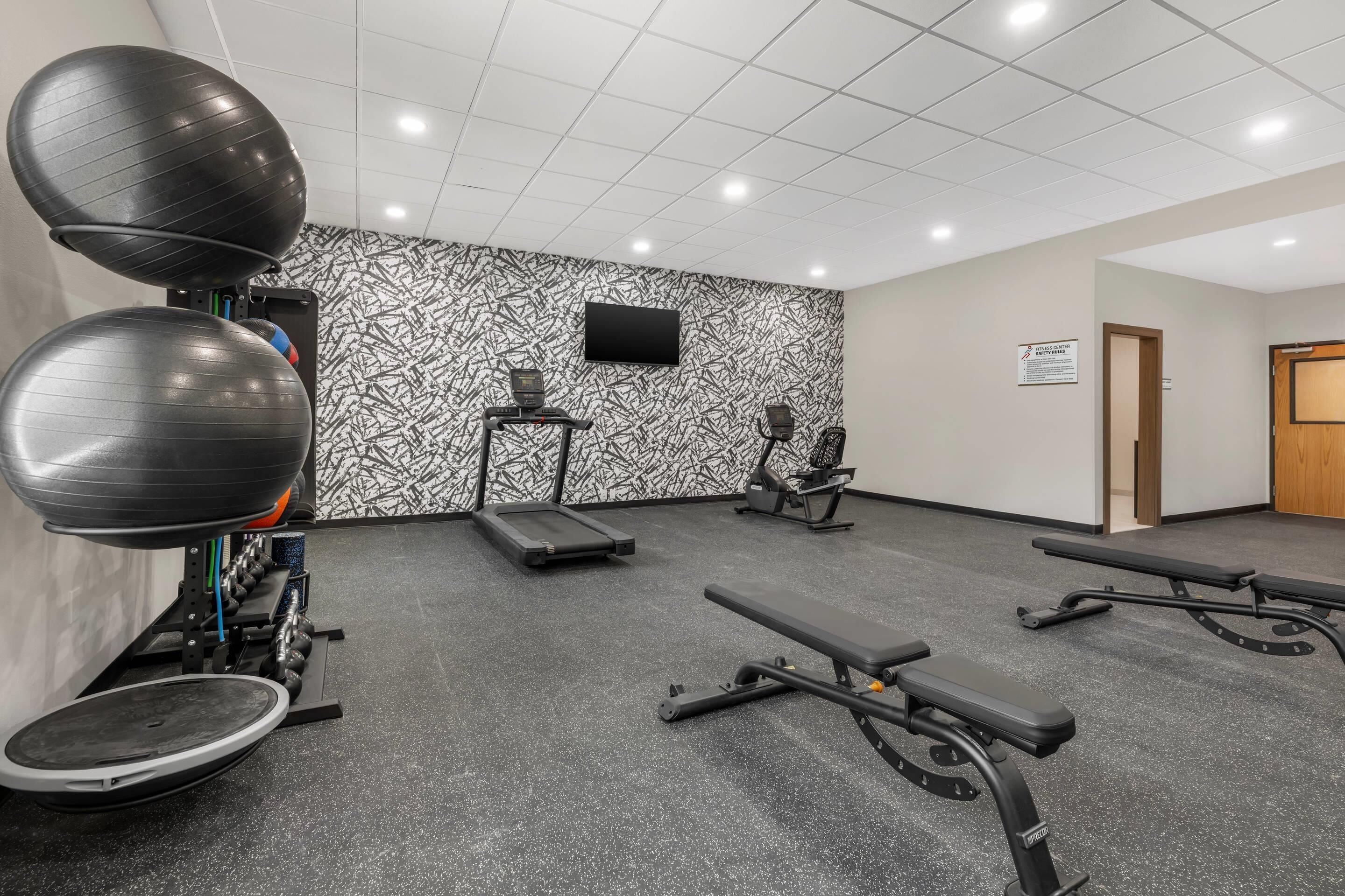 A gym with exercise equipment, a treadmill, and a wall-mounted TV.