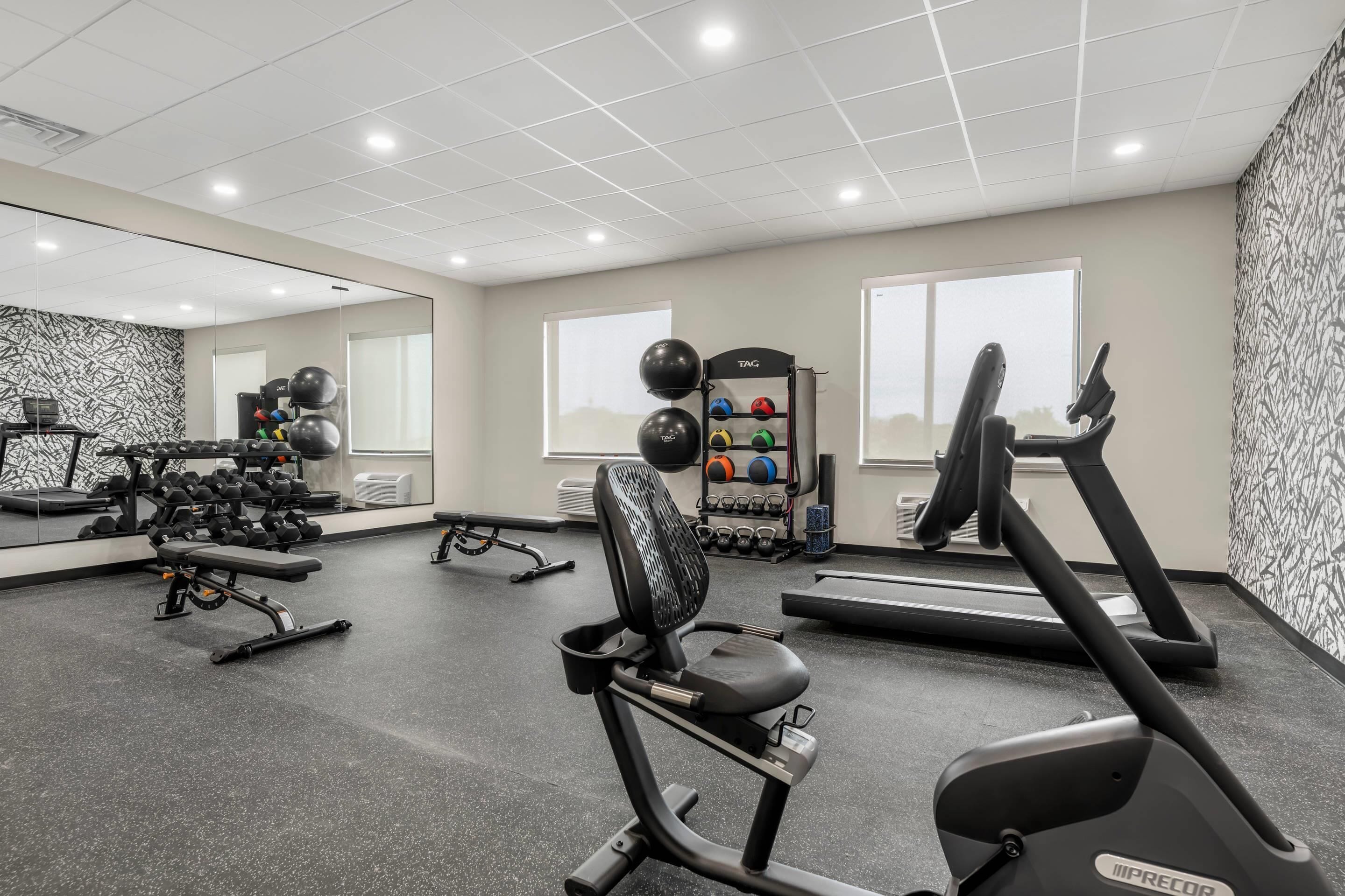 A gym with treadmills, exercise bikes, and free weights.