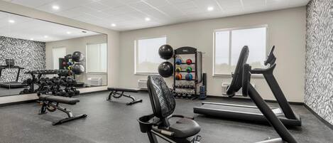 A gym with treadmills, exercise bikes, and free weights.