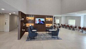 A spacious lobby with a television, seating area, and a conference room.