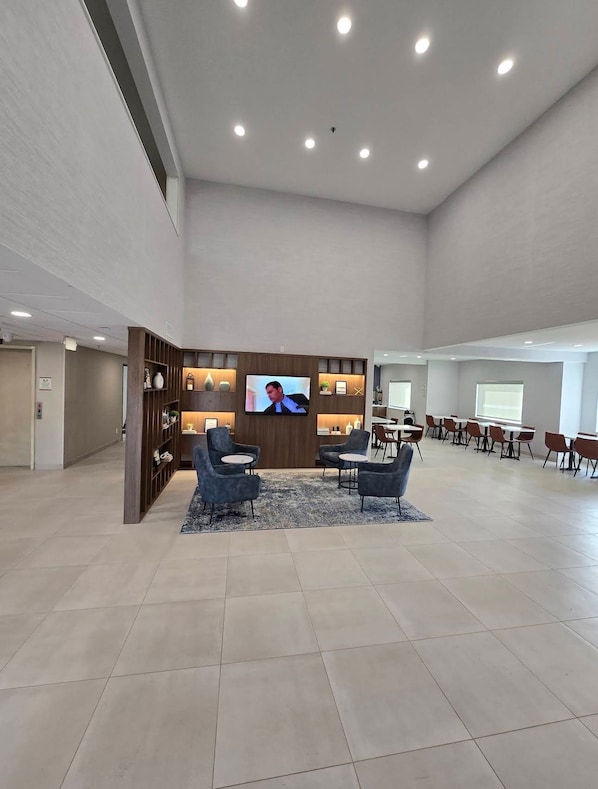 Un vestíbulo amplio con televisor, zona de estar y sala de conferencias.