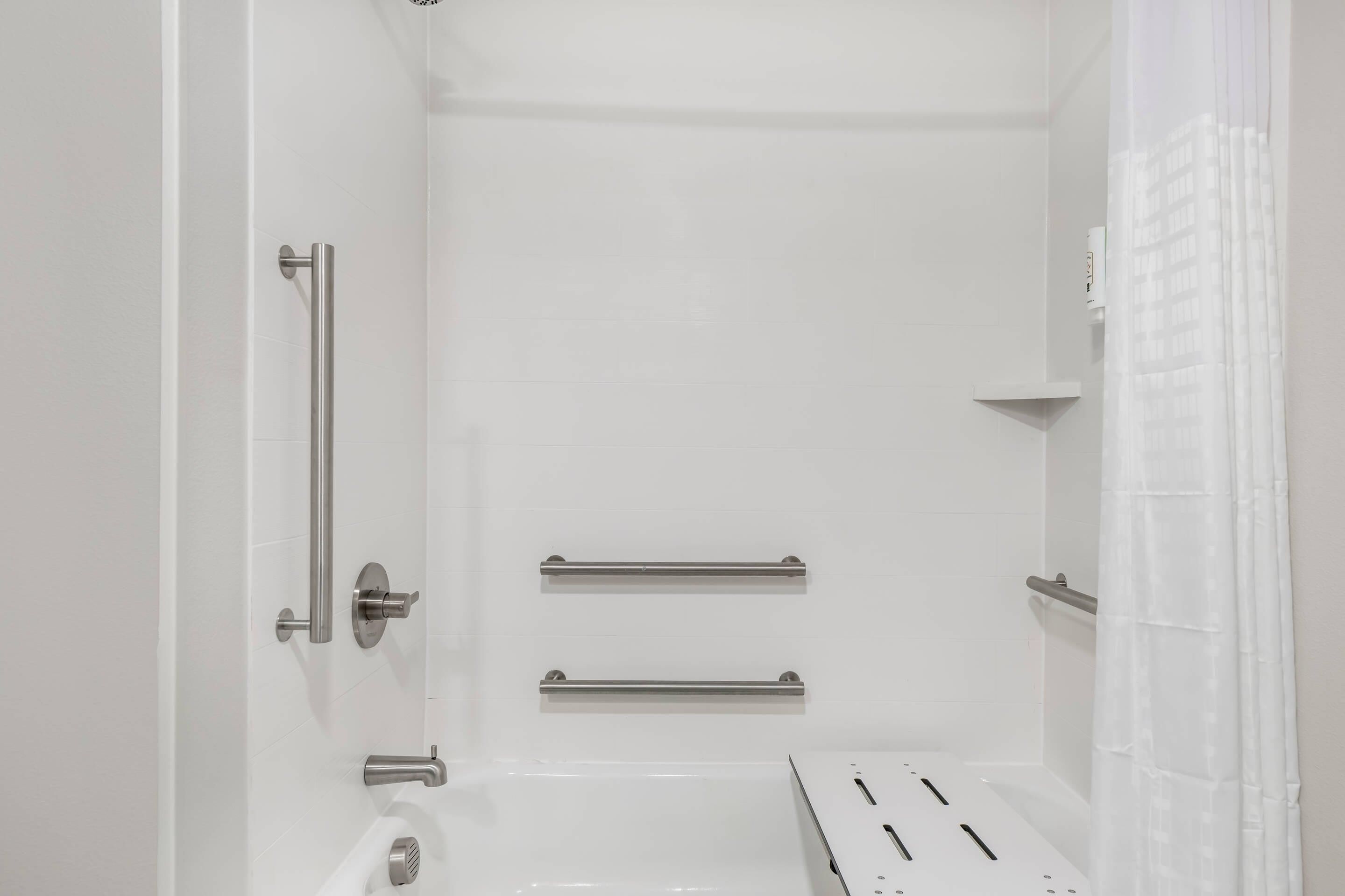 A bathroom with white walls, a bathtub, a toilet, and a shower curtain.