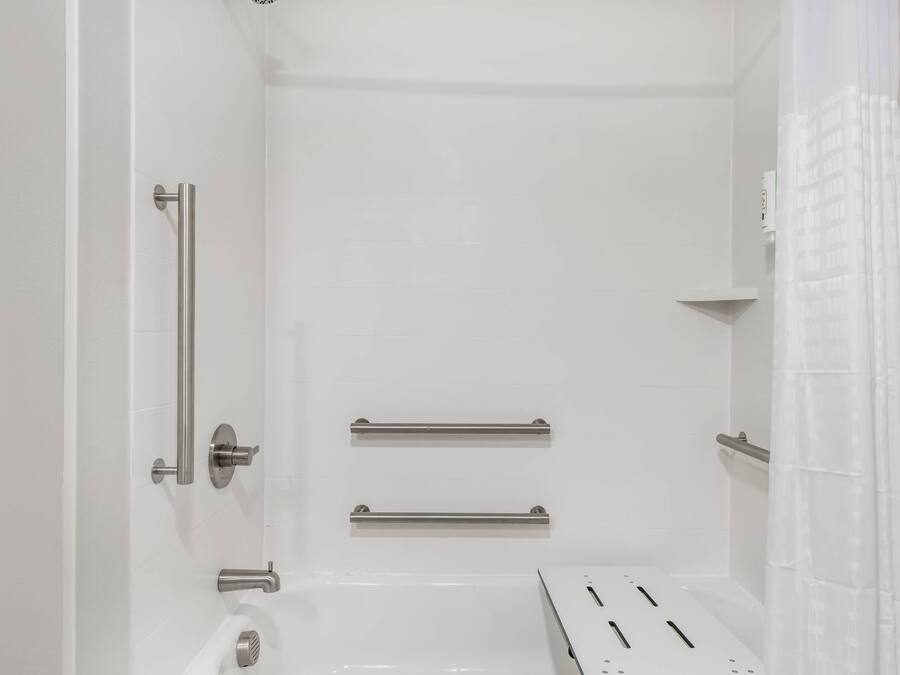 A bathroom with white walls, a bathtub, a toilet, and a shower curtain.