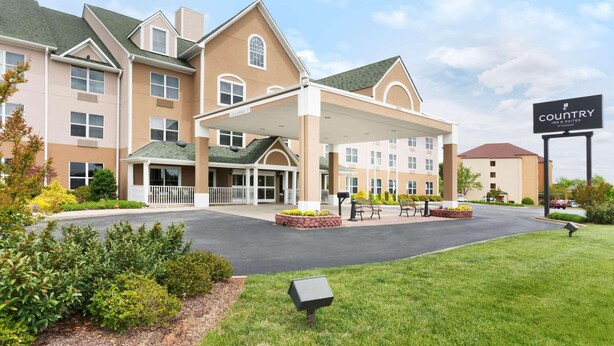 A hotel with a covered entrance, multiple floors, and a landscaped front yard. - Country Inn & Suites by Radisson, Burlington (Elon), NC (Burlington)