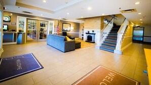 A spacious lobby with a reception desk, a sofa, a fireplace, and a staircase. - Country Inn & Suites by Radisson, Burlington (Elon), NC (Burlington)
