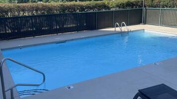 Een seizoensgebonden buitenzwembad en ligstoelen