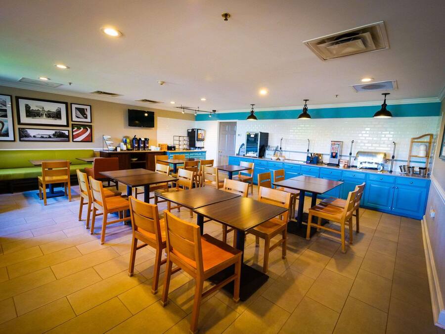 Un ristorante con tavoli e sedie in legno, un bancone con una macchina da caffè e una parete decorata in blu.