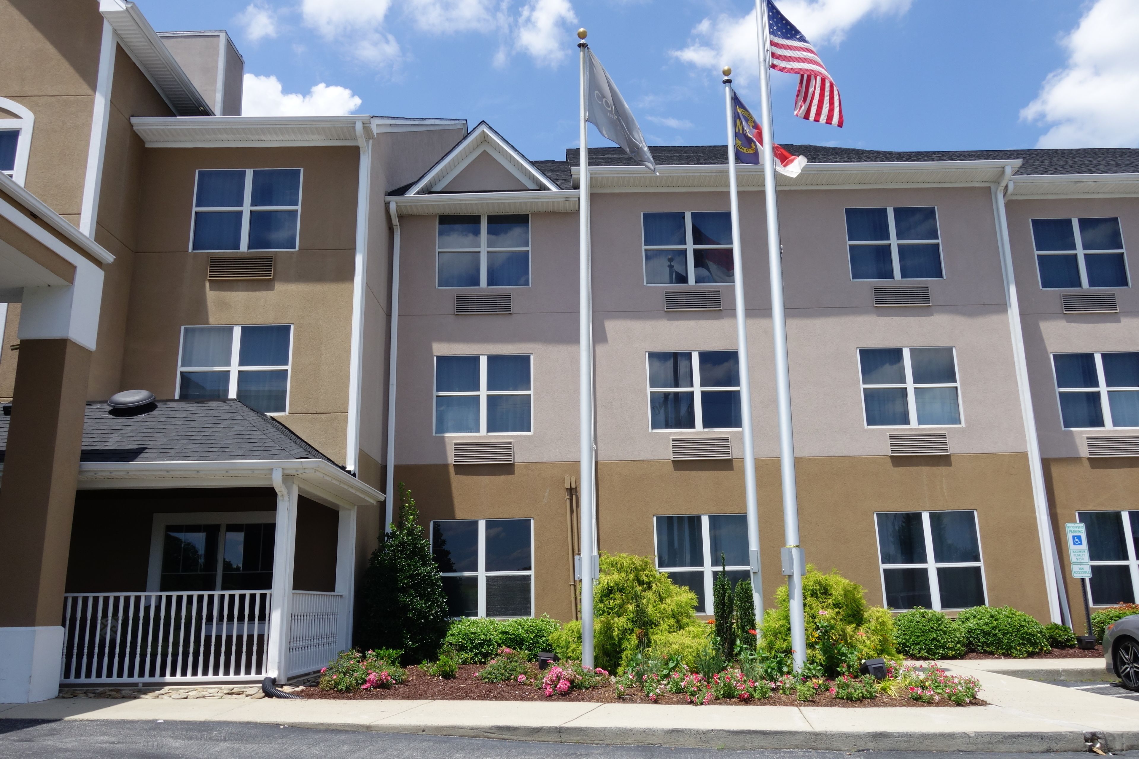 A multi-story building with a beige facade, multiple windows, and a flagpole with an American flag.