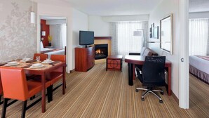 A hotel room with a dining area, a TV, a fireplace, and a bed. - Residence Inn Waco (Waco)
