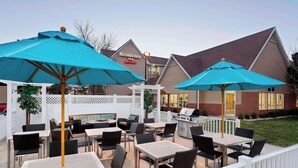 A patio area with tables and chairs, blue umbrellas, and a barbecue grill. - Residence Inn Waco (Waco)