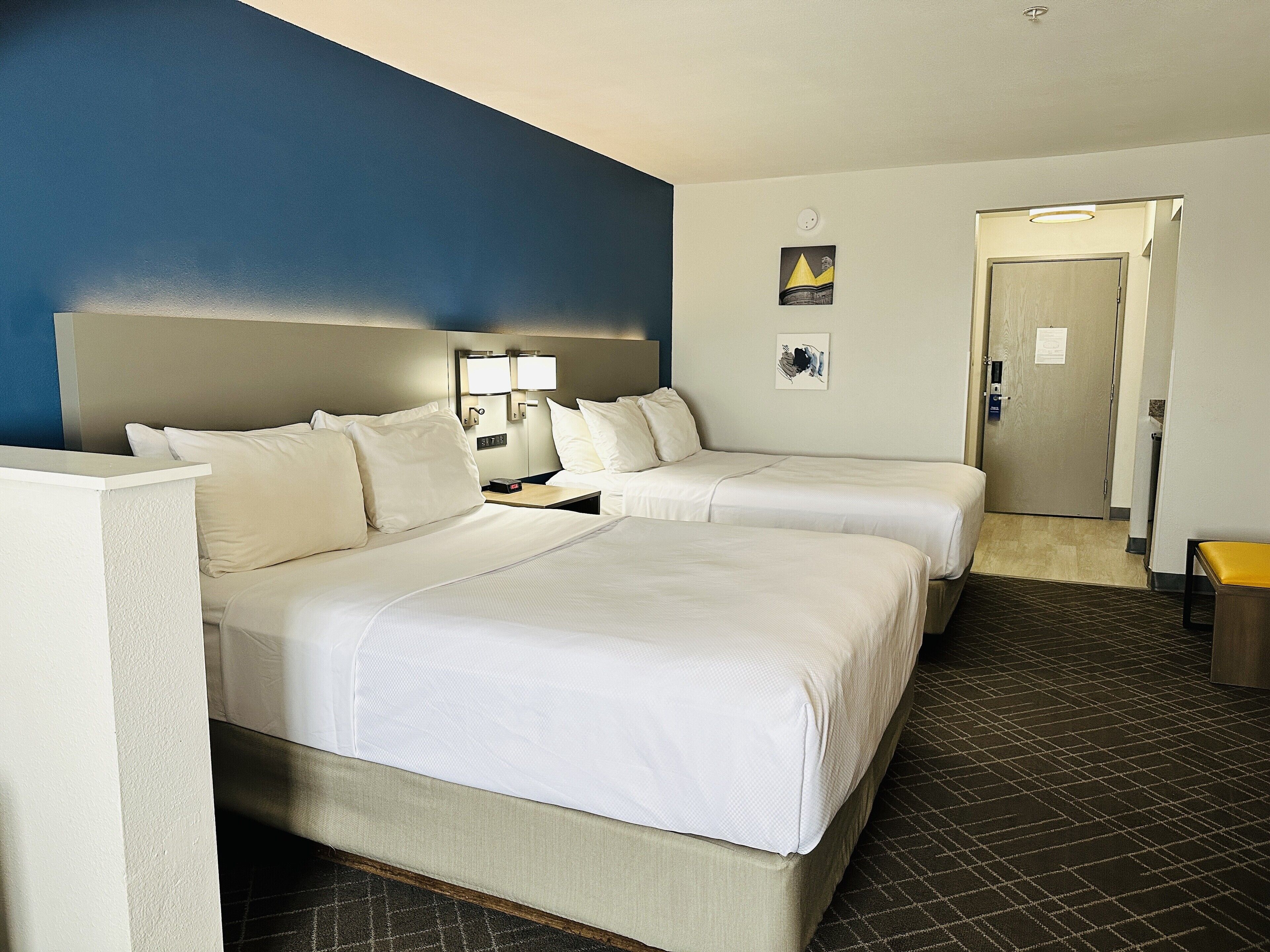Habitación de hotel con dos camas, un escritorio y una mesita de noche.