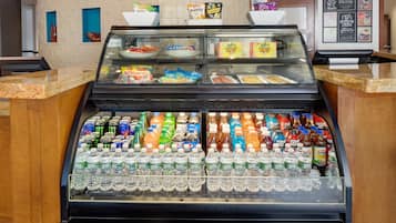 A food display case with various packaged snacks and a beverage cooler filled with bottled water.