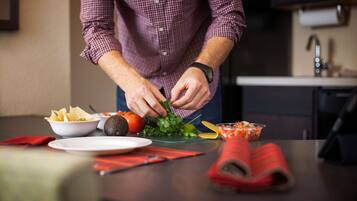 A person preparing food with vegetables and chips on a table.
