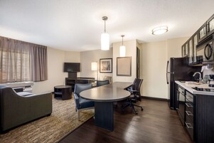 Una sala de estar moderna y bien iluminada, con comedor, cocina y televisor de pantalla plana.