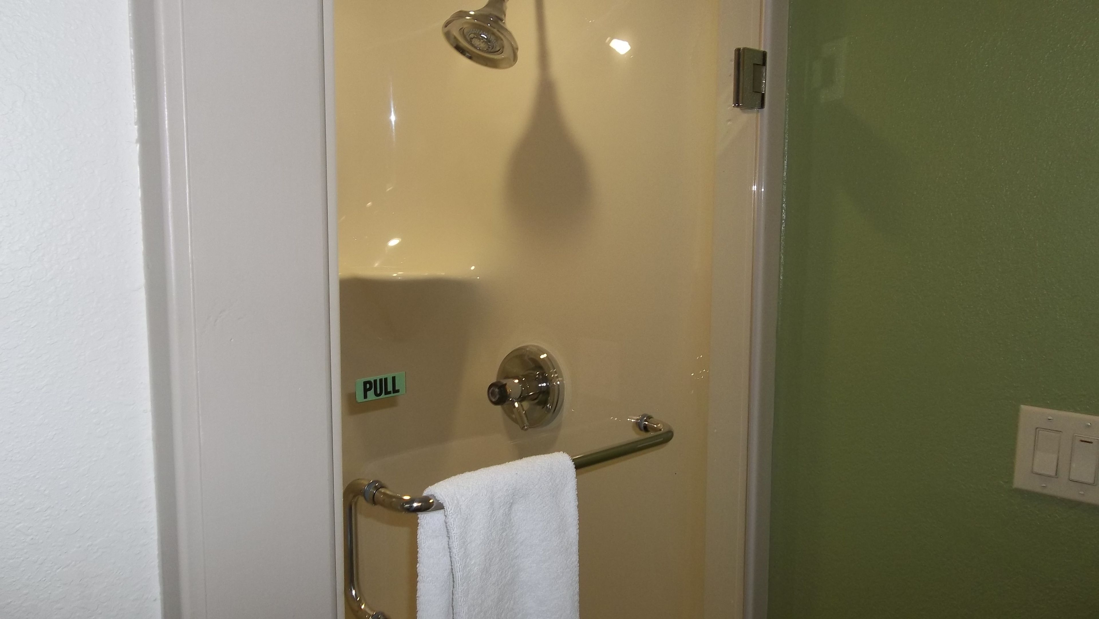 A bathroom with a glass door, a towel rack, and a 'PULL' sign.