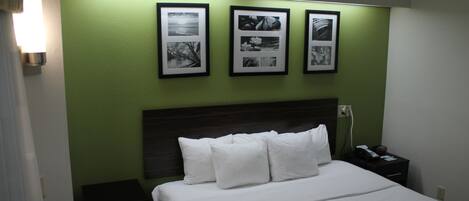 Una habitación de hotel con una cama, una mesita de noche y una lámpara de pared.