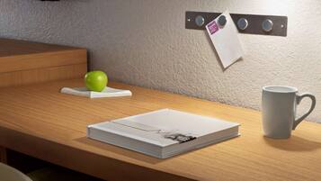A neatly arranged desk with a book, a mug, and a green apple on a coaster.
