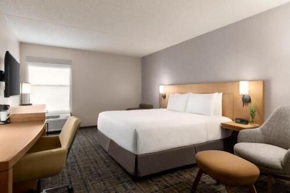 Una habitación de hotel con una cama, un escritorio, una silla y un televisor.