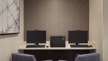 A workspace with two computer monitors, a printer, and two chairs.