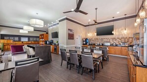 Een moderne keuken met houten kastjes, een eethoek met stoelen en een bar met een aanrecht.