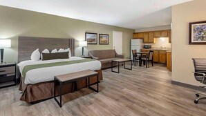 Een hotelkamer met een bed, nachtkastjes, een bank, een bureau en een kitchenette.