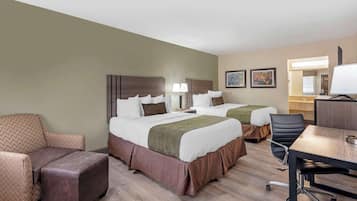 Een hotelkamer met twee bedden, een bureau, een stoel en een bank.