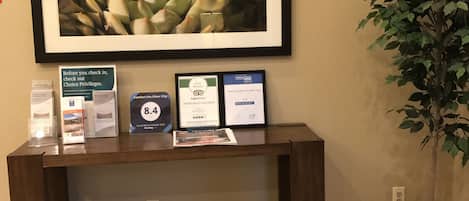 Una mesa de recepción con diplomas enmarcados, una planta suculenta en marco y una planta en maceta.