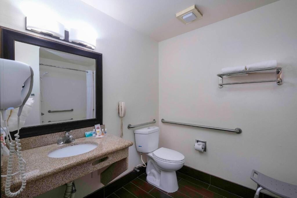 A small bathroom with a sink, toilet, and a mirror.