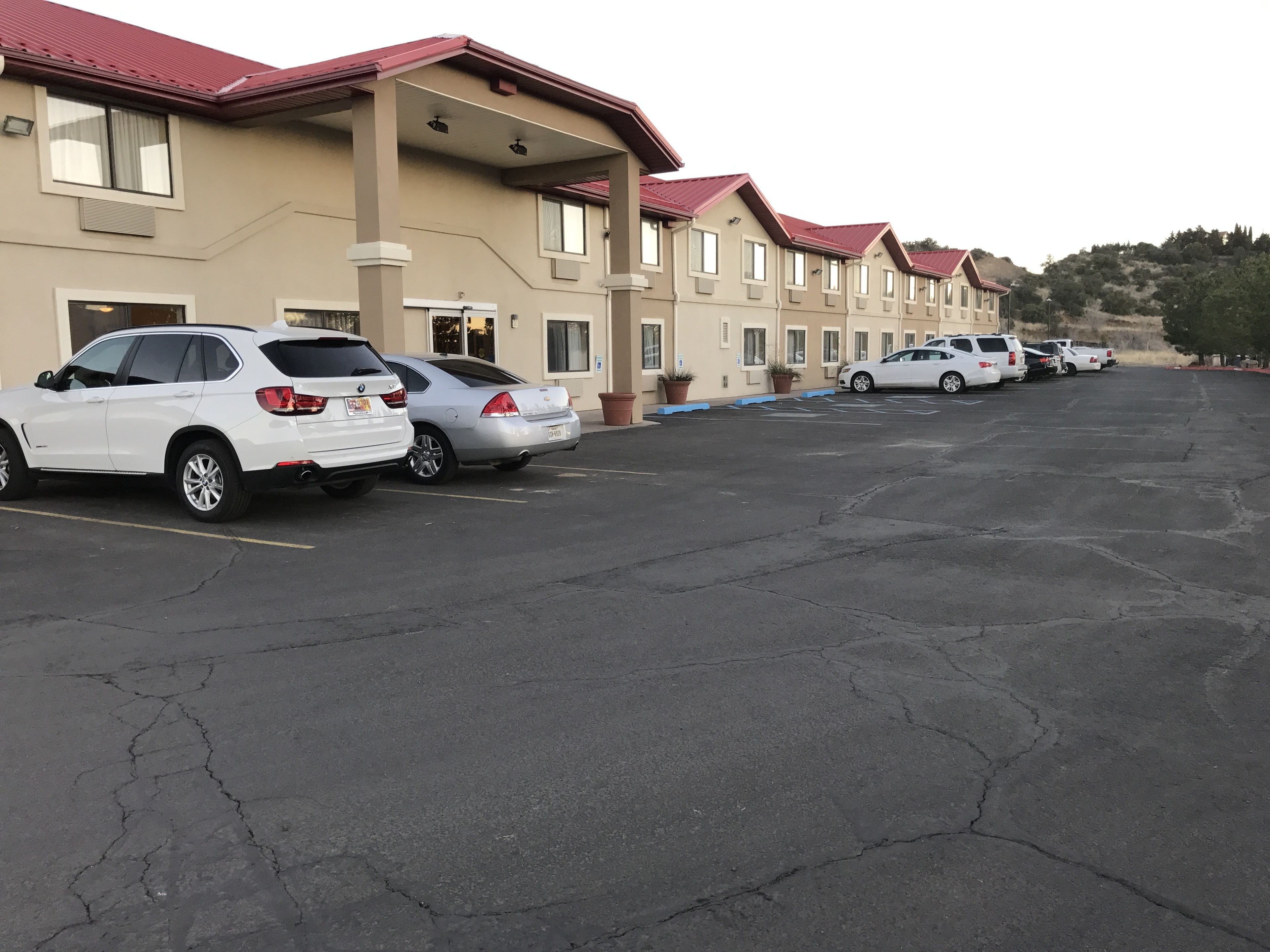 A row of hotel rooms with a parking lot in front.