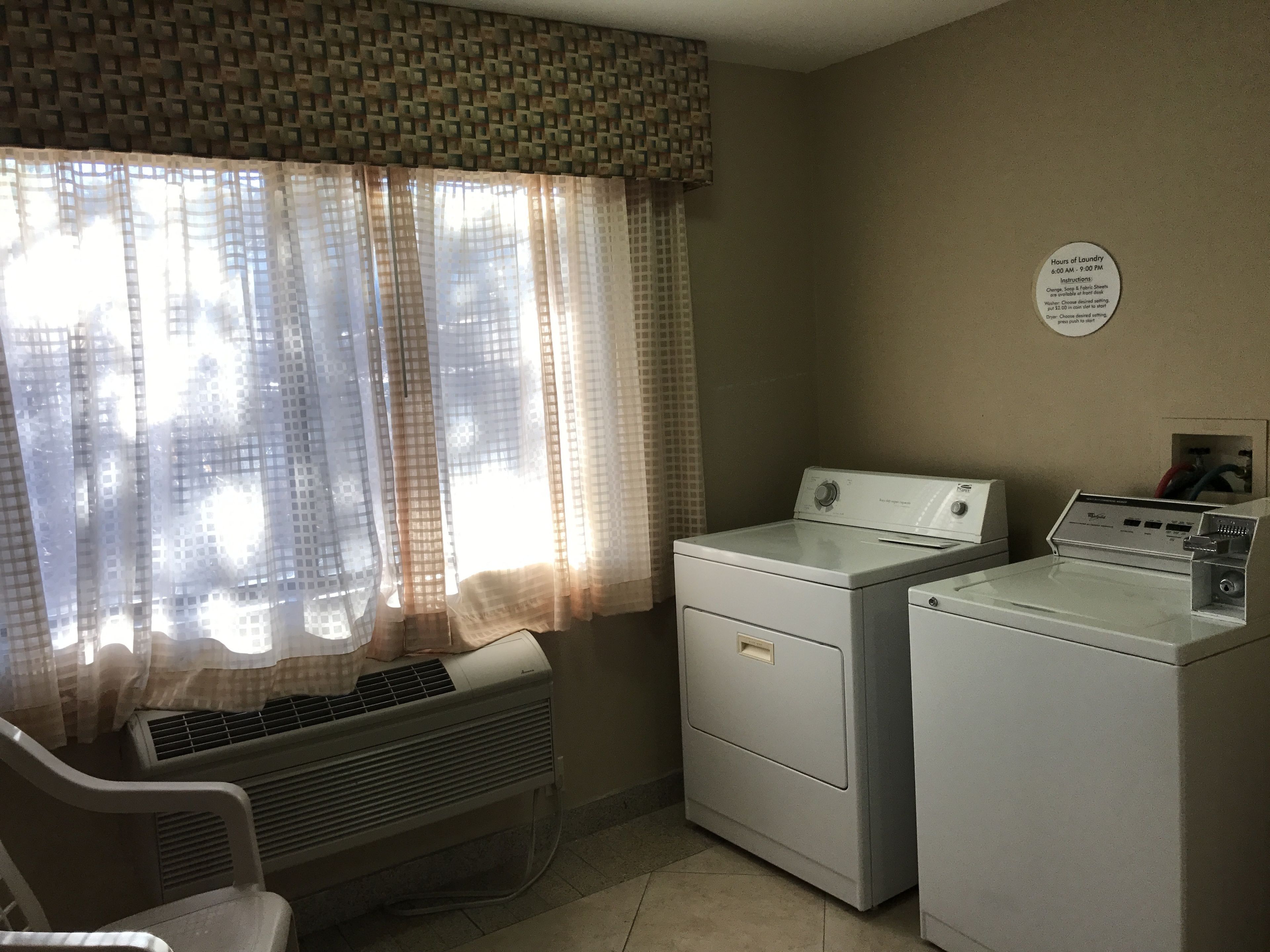 A laundry room with a washing machine, dryer, and a vented air conditioner.