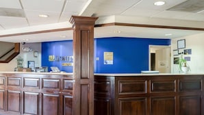 A reception area with a blue wall, wooden reception desk, and a sign that reads "QUALITY BY CHOICE". - Quality Inn Magee (Magee)