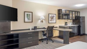 A modern hotel room with a kitchenette, a flat-screen TV, a desk with a chair, and artwork on the walls. - Executive Residency by Best Western Philadelphia-Willow Grove (Horsham)