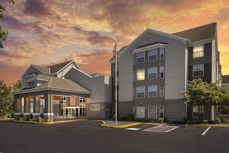 A hotel with a modern design, featuring a two-story building with a flat roof and a separate entrance building with a covered porch.